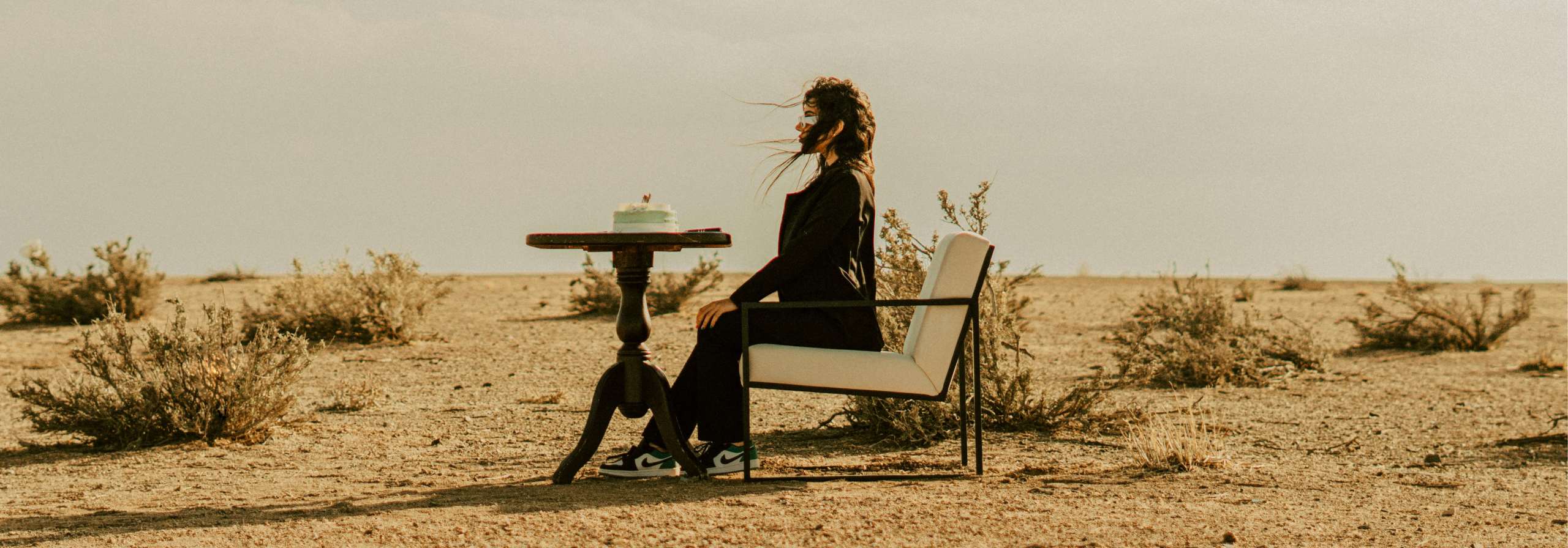 Donna seduta sola a un tavolo nel deserto con una torta.